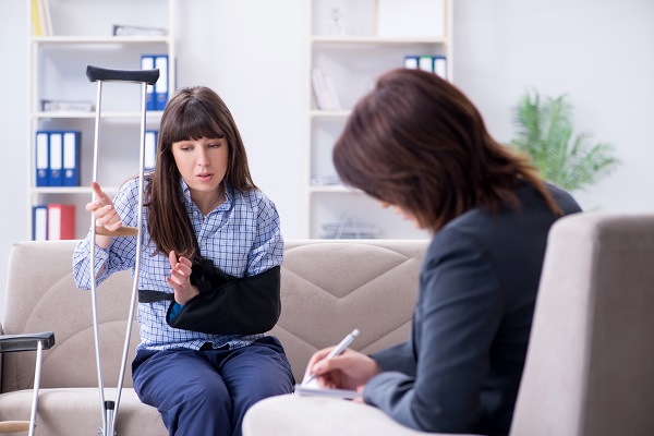 A woman in a sling and with crutches meets with a personal injury lawyer.