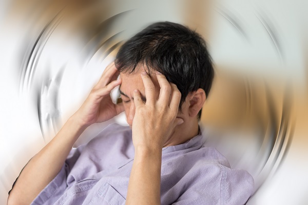 Man holds hands on his head after suffering from a concussion.