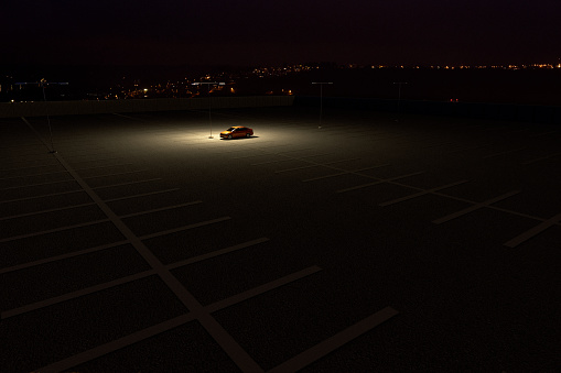 3D rendering of a sinngle car in a parking lot representing the concept of working late