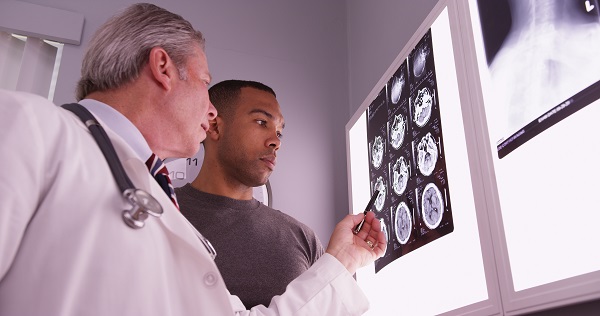 Medical doctor reviewing brain image scans with a patient.