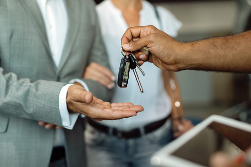 Close-up of businessman receiving car keys from a mechanic at auto repair shop.