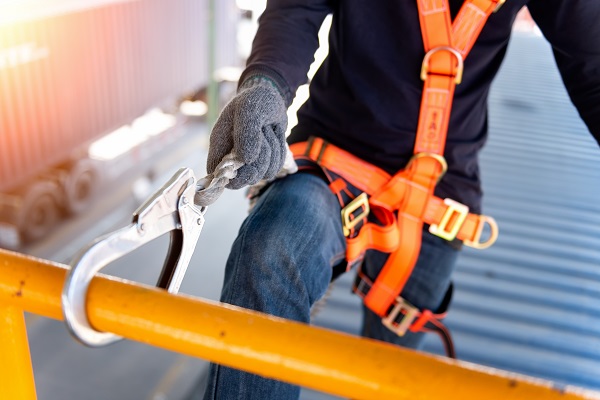 Construction worker using safety harness and safety line working on a new construction site project.