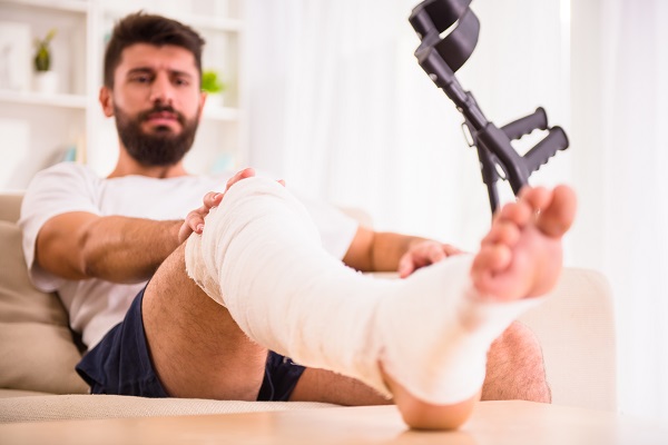 man with injured leg wrapped in gauze resting it on a table