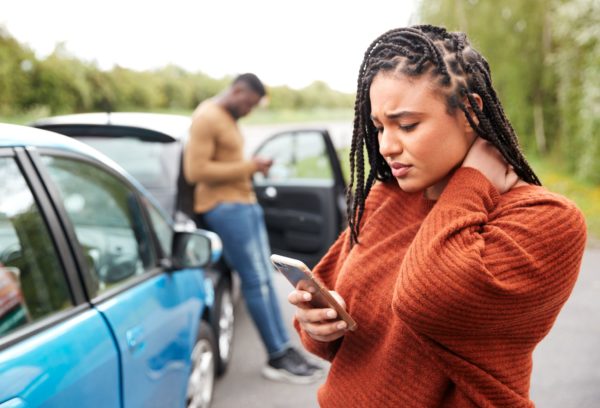 A man and a woman at the scene of a car accident.