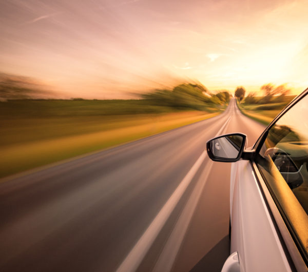 Speeding car on a roadway with motion blur to indicate it's going very fast.