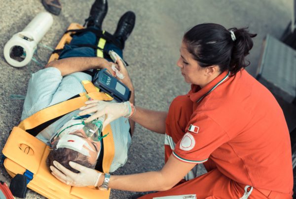 A man on a stretcher is attended to by a female EMT