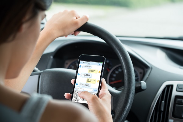 Close-up of woman sitting Inside car, typing text message on mobile phone.