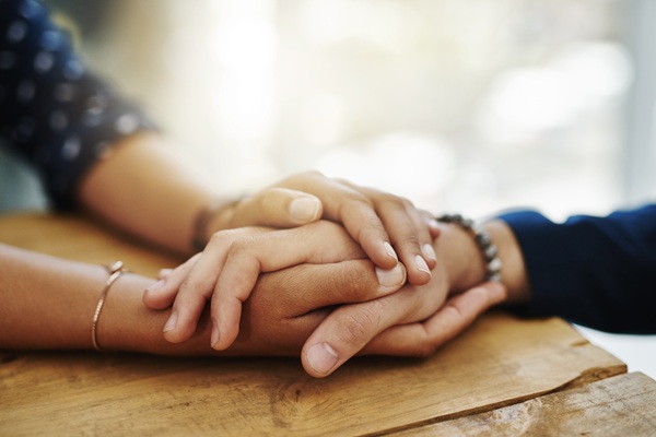 Close up of a woman holding another woman's hands to console her after the death of a loved one in a fatal motorcycle crash. (AdobeStock_600706165)