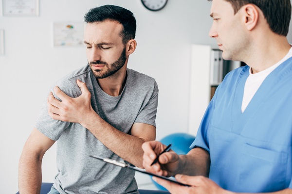 Man holding his shoulder in pain while in the doctor's office following a car accident. (272753341)