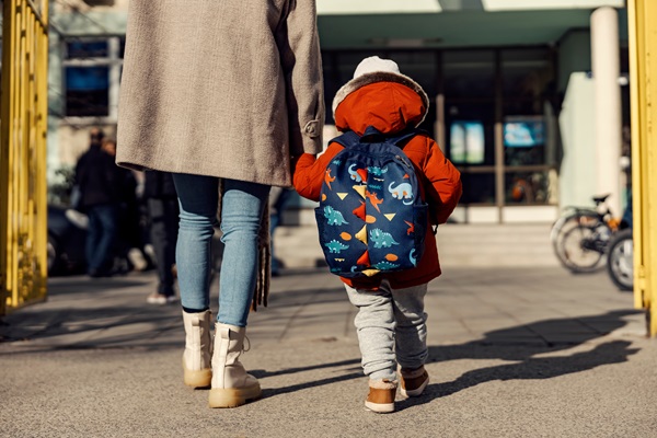 A mother entering the kindergarten yard with her preschooler boy. (AdobeStock_488547171)
