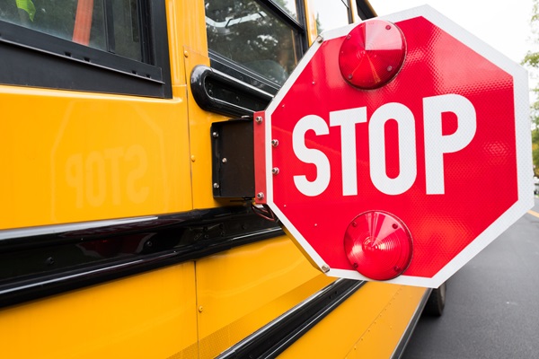 Extended stop sign with red lights mounted on the side of a yellow school bus. (176919258)