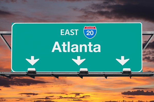Green Interstate 20 East highway sign for Atlanta against an orange and purple sunset sky. (112934529)