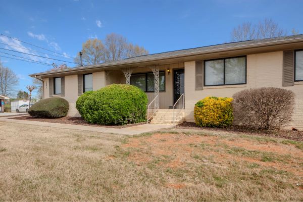 Exterior of single-story office building with beige brick facade, front steps, and landscaped shrubs.
