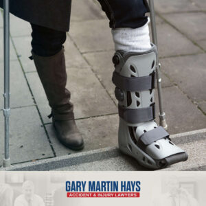 Close-up of a person holding their knee while wearing a black orthopedic knee brace with adjustable support straps.