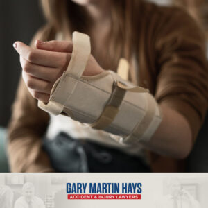 Close-up of a person's swollen hand supported by a black wrist and forearm brace.