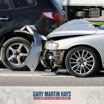 Crash scene of a rear-end car accident with a blue minivan hit from behind by a silver car.